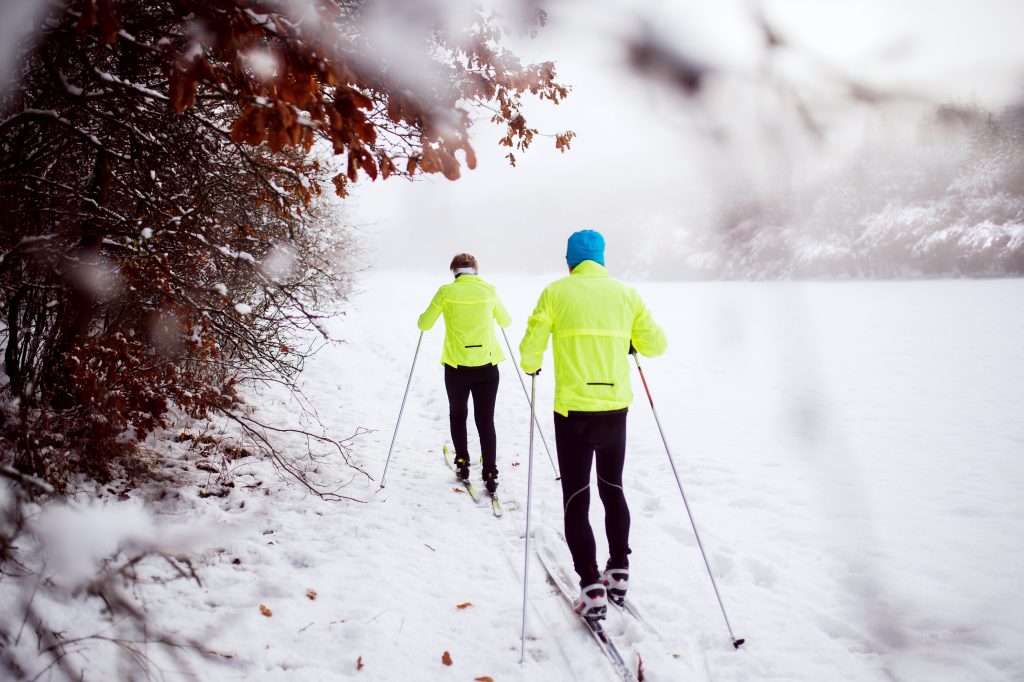 Active senior couple cross-country skiing. Winter time. Rear view.